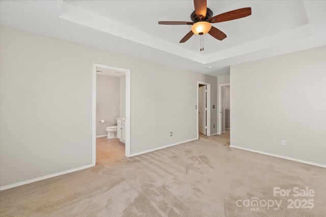 unfurnished room with light carpet, a ceiling fan, baseboards, and a raised ceiling