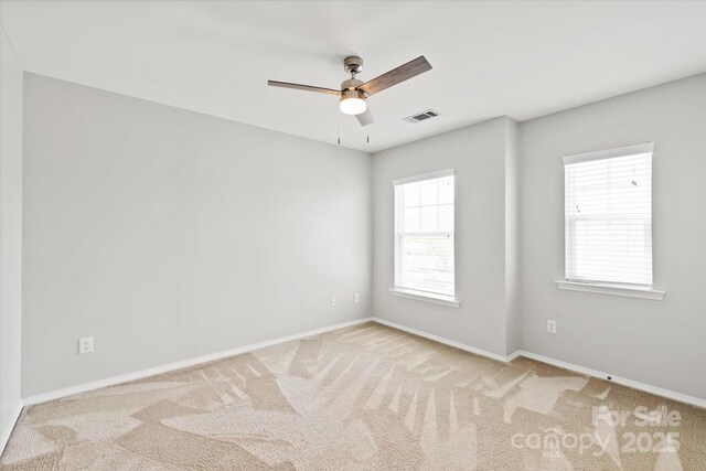 empty room featuring baseboards, visible vents, carpet floors, and ceiling fan