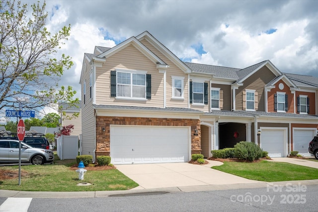 view of front of home featuring an attached garage, driveway, and stone siding
