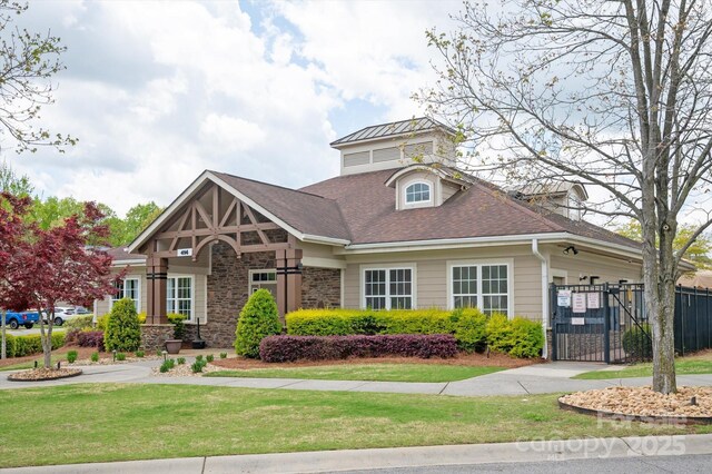 view of front of house featuring a gate, stone siding, an attached garage, fence, and a front yard