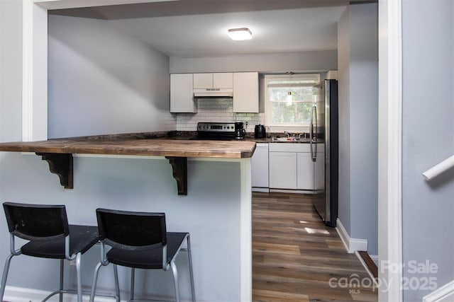 kitchen with dark wood-type flooring, white cabinets, under cabinet range hood, stainless steel appliances, and wood counters