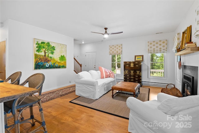 109 Paradise Cir, Clyde, NC 28721 - living area featuring light wood-style flooring, a glass covered fireplace, stairway, and a ceiling fan