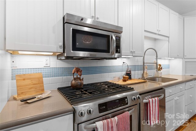 109 Paradise Cir, Clyde, NC 28721 - kitchen with stainless steel appliances, tasteful backsplash, white cabinetry, and light countertops