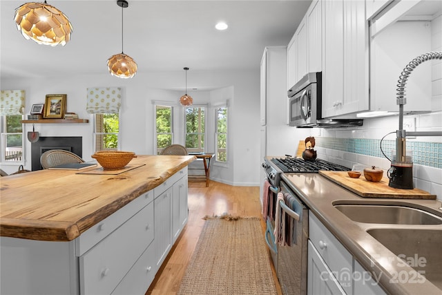 109 Paradise Cir, Clyde, NC 28721 - kitchen with wooden counters, appliances with stainless steel finishes, light wood-type flooring, backsplash, and white cabinetry