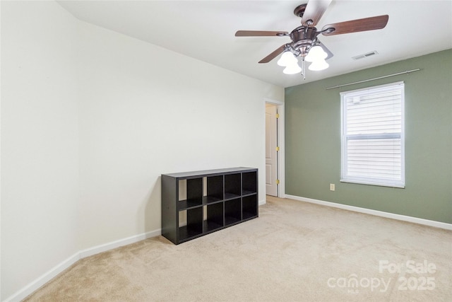 carpeted empty room with baseboards, a ceiling fan, and visible vents
