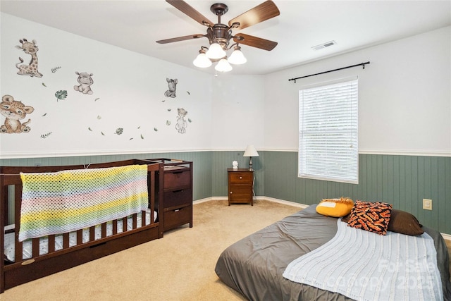 bedroom featuring a wainscoted wall, ceiling fan, carpet, and visible vents