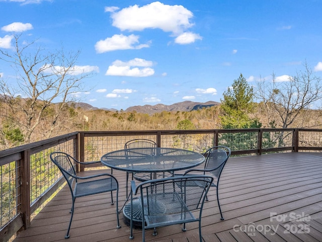 deck with a mountain view and outdoor dining space