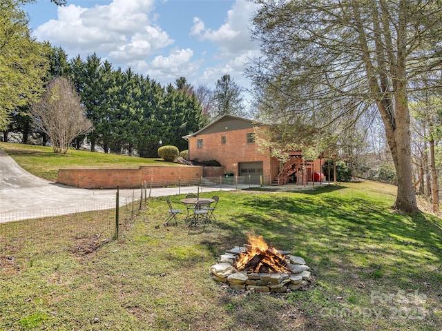 view of yard with a garage, a fire pit, stairs, and fence