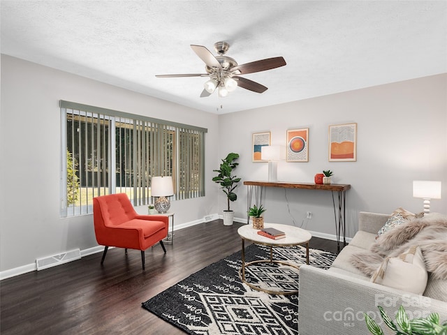 living area with baseboards, a textured ceiling, visible vents, a ceiling fan, and wood finished floors