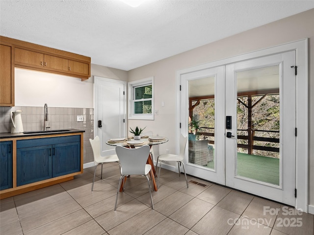 dining area with light tile patterned floors, french doors, and a textured ceiling