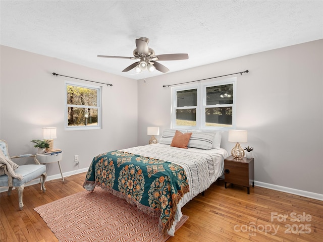 bedroom with a textured ceiling, baseboards, and wood-type flooring