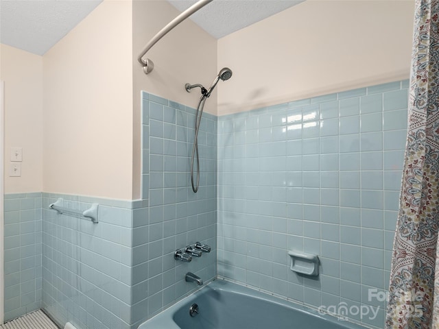 bathroom featuring shower / bath combination with curtain, a textured ceiling, tile walls, and wainscoting