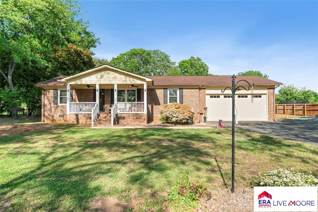 ranch-style home featuring a porch, fence, a garage, a front yard, and aphalt driveway