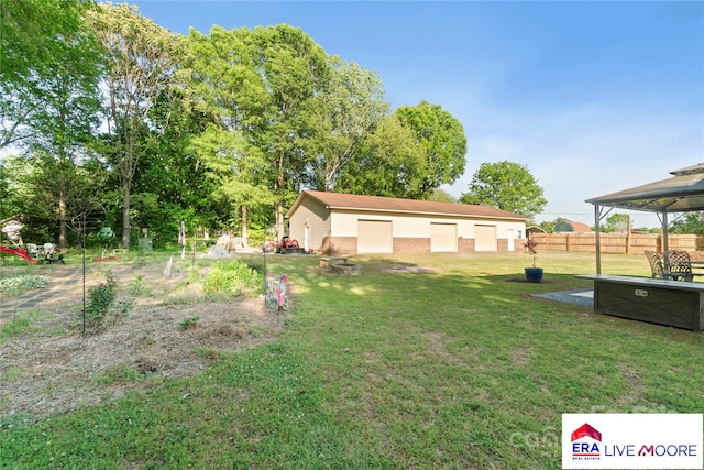 view of yard featuring fence, an outdoor fire pit, a gazebo, and a detached garage