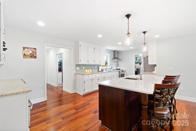 552 Odell School Rd, Concord, NC 28027 - kitchen with wall chimney exhaust hood, a sink, light countertops, dark wood-style floors, and a breakfast bar area