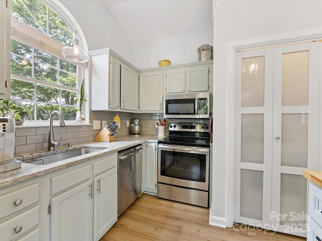 2214 Olde Chantilly Ct, Charlotte, NC 28205 - kitchen with stainless steel appliances, a sink, lofted ceiling, decorative backsplash, and light stone counters