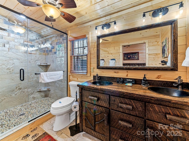 full bath with wooden walls, toilet, a stall shower, and a sink
