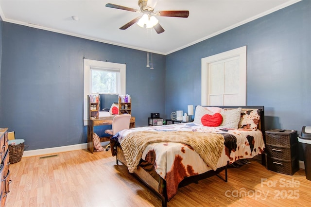 bedroom featuring crown molding, a ceiling fan, visible vents, wood finished floors, and baseboards