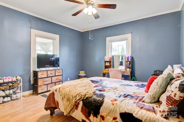bedroom with baseboards, crown molding, a ceiling fan, and wood finished floors