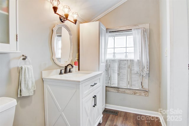 half bathroom with plenty of natural light, vanity, toilet, and wood finished floors