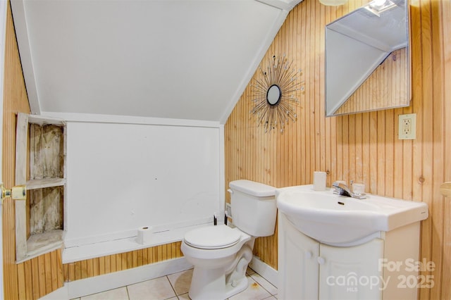 bathroom featuring toilet, wooden walls, vanity, tile patterned floors, and lofted ceiling