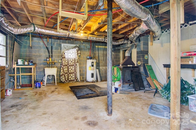 unfinished basement with a sink, electric water heater, and concrete block wall