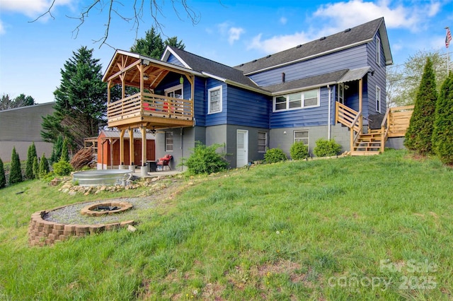 back of house with a deck, a patio, a yard, and a fire pit