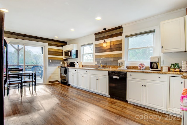 kitchen featuring stainless steel microwave, light wood-type flooring, black dishwasher, range with electric stovetop, and a sink