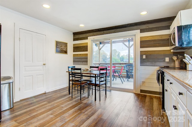 dining area with wood finished floors, ornamental molding, and recessed lighting