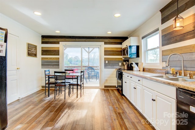kitchen featuring black appliances, light wood-style floors, light countertops, and a sink