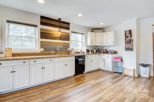 kitchen with light wood-style flooring, white cabinetry, black dishwasher, decorative light fixtures, and a sink