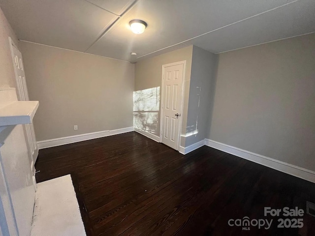unfurnished living room featuring dark wood-style floors and baseboards