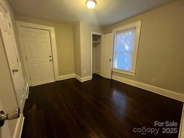 unfurnished bedroom featuring dark wood-type flooring and baseboards