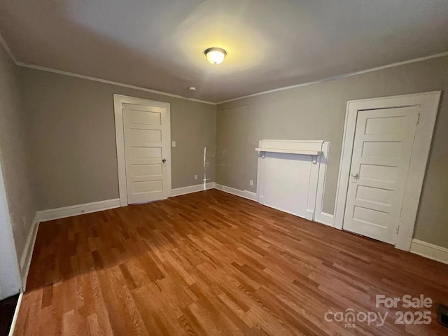 spare room featuring baseboards, crown molding, and wood finished floors
