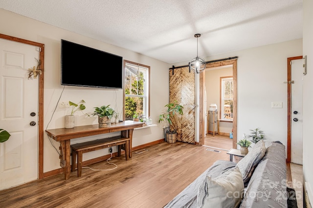 living area featuring baseboards, visible vents, wood finished floors, and a textured ceiling