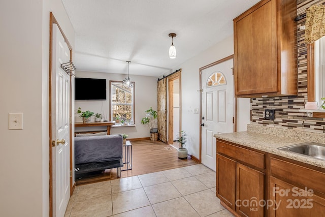 kitchen with backsplash, light countertops, light tile patterned flooring, and brown cabinets