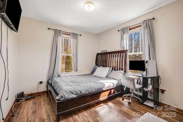 bedroom with baseboards, a textured ceiling, and wood-type flooring
