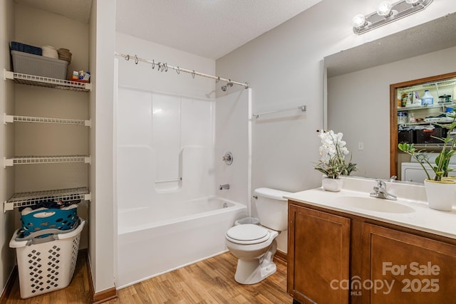 full bath with vanity, toilet, bathing tub / shower combination, a textured ceiling, and wood finished floors