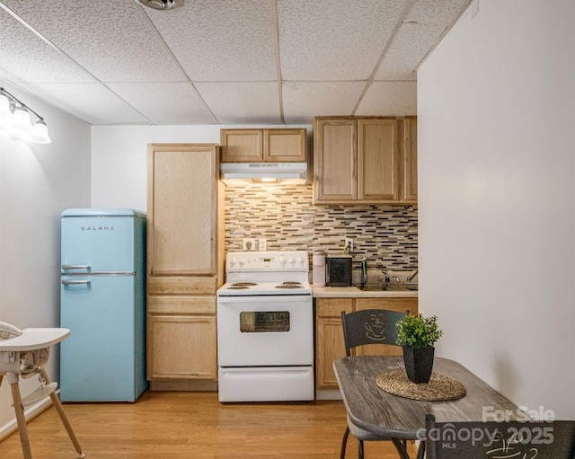 kitchen with white appliances, under cabinet range hood, backsplash, light wood-style floors, and a paneled ceiling