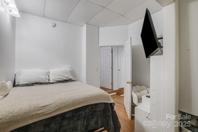 bedroom with a drop ceiling and wood finished floors