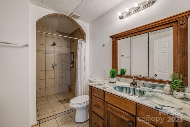 bathroom with visible vents, toilet, tiled shower, vanity, and tile patterned flooring
