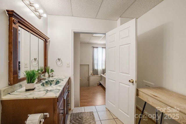 bathroom featuring a drop ceiling, tile patterned floors, and vanity
