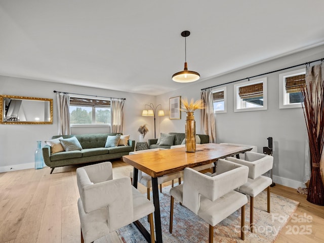 dining area with baseboards and light wood-style flooring