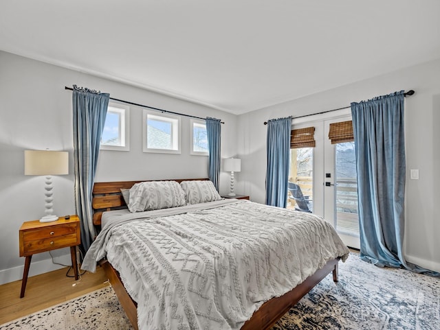 bedroom featuring multiple windows, light wood-style floors, baseboards, and access to exterior