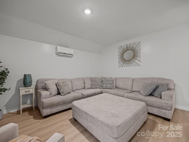 living area with baseboards, wood finished floors, a wall unit AC, and recessed lighting