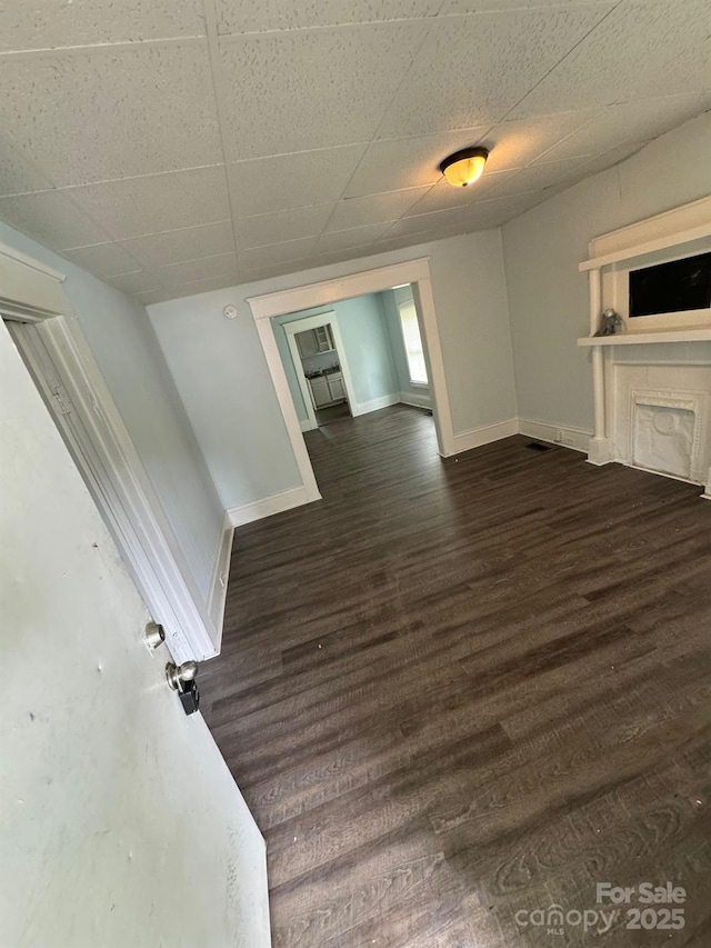 4510 Wildwood Ave, Charlotte, NC 28208 - unfurnished living room featuring dark wood finished floors, baseboards, and a drop ceiling