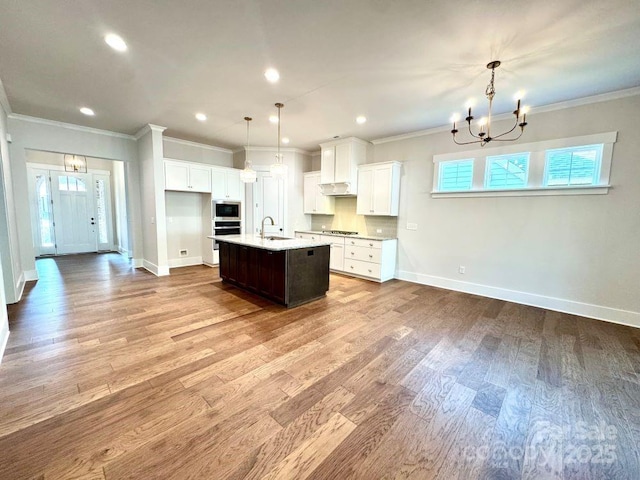 kitchen featuring a sink, appliances with stainless steel finishes, a chandelier, and baseboards