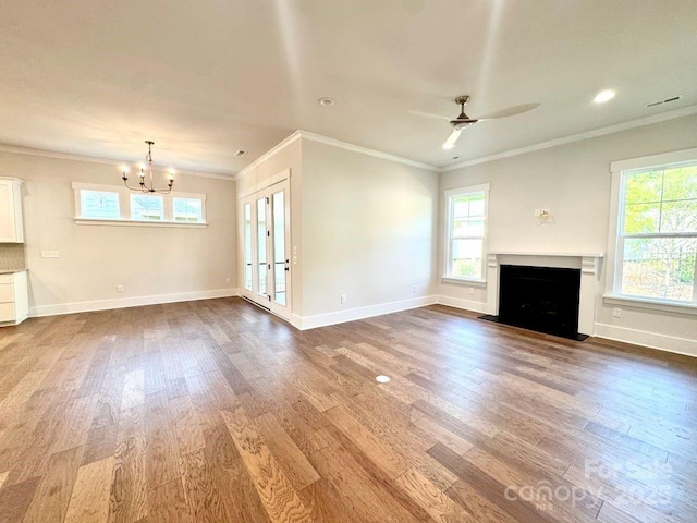 unfurnished living room featuring crown molding, a fireplace with flush hearth, wood finished floors, and ceiling fan with notable chandelier