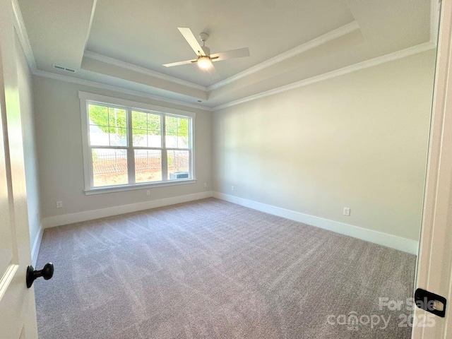 spare room with visible vents, a raised ceiling, baseboards, ornamental molding, and carpet
