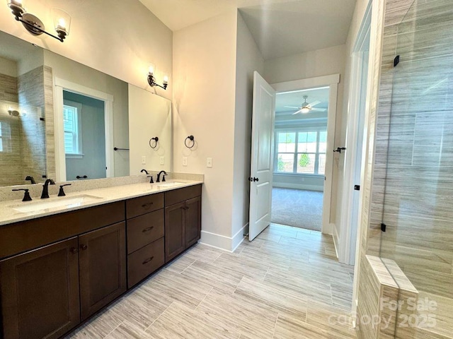 full bathroom featuring double vanity, a ceiling fan, baseboards, tiled shower, and a sink
